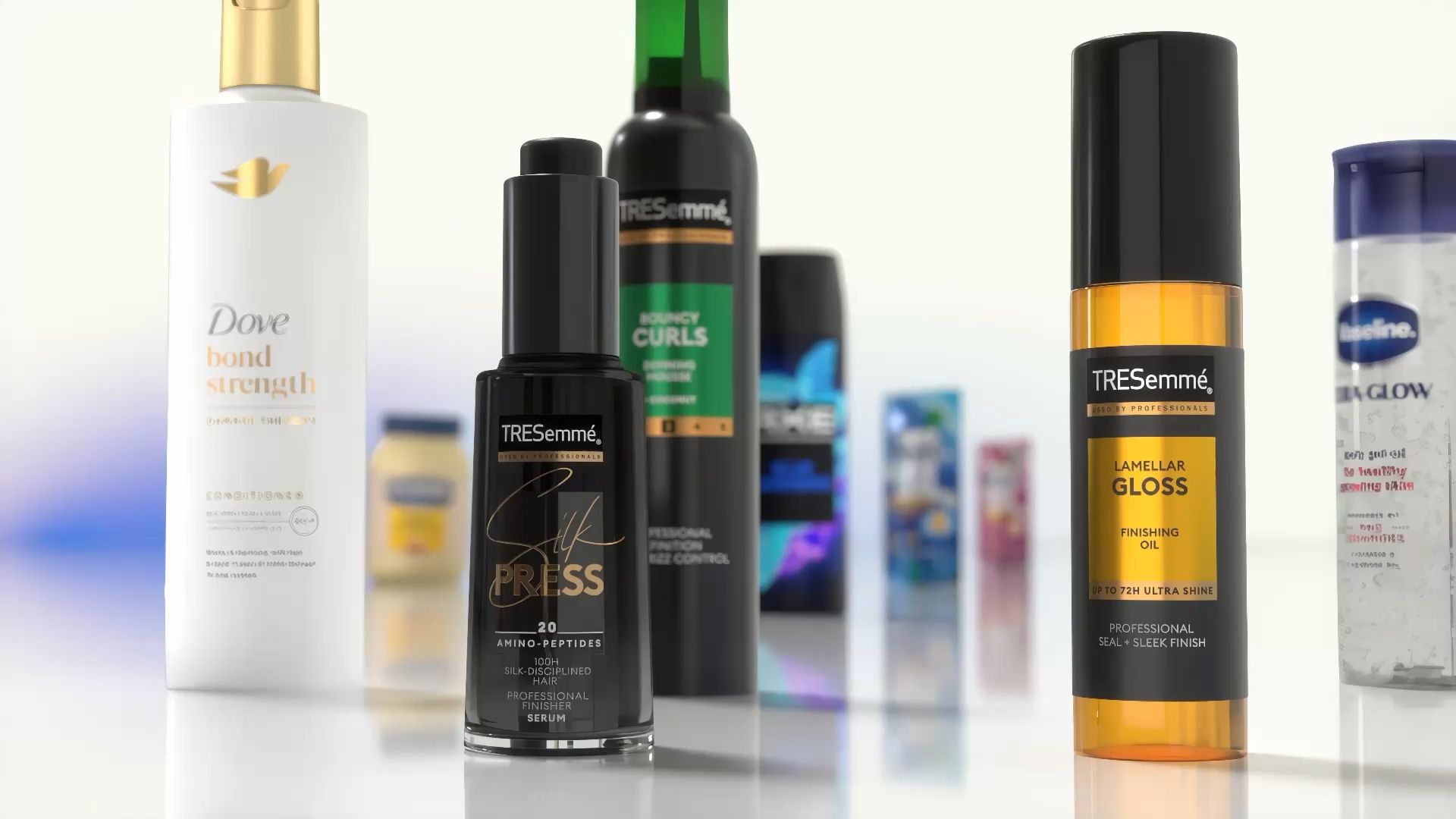 Nærbillede af diverse hår- og kropsplejeprodukter udstillet på en reflekterende overflade. Synlige genstande inkluderer Dove Bond Strength balsam, TRESemmé Silk Press serum, TRESemmé Lamellar Gloss finishing oil og andre Unilever-produkter i baggrunden.